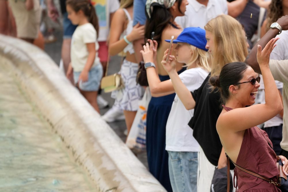 Turisti hádžu mince do Fontány di Trevi v Ríme  